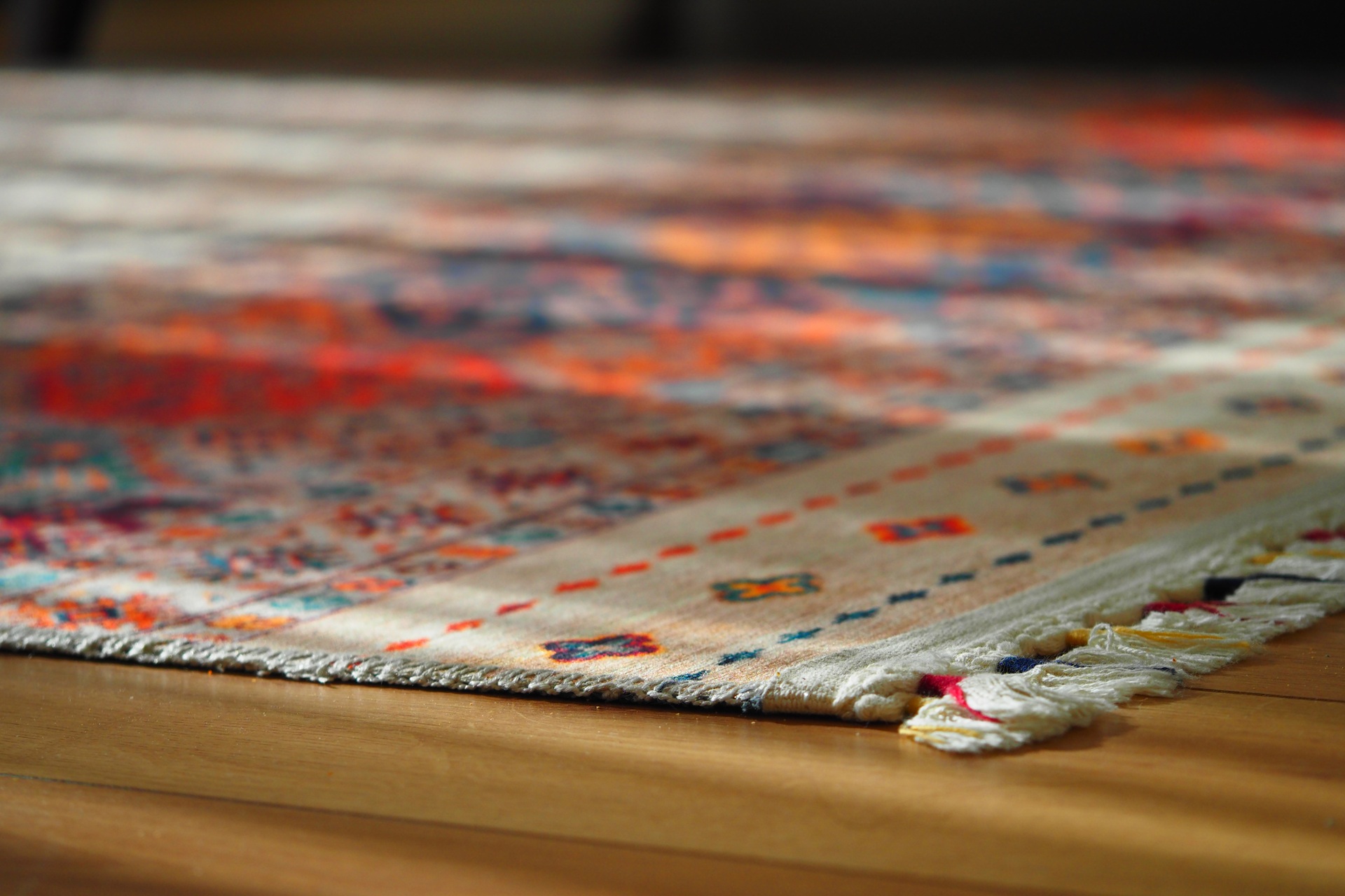 Close-up of a colorful patterned rug with fringed edges on a wooden floor, showing intricate designs—perfect for those searching for rug cleaners near me to help maintain such beautiful details.