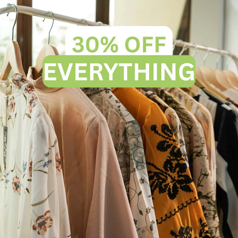 Two black suits with ties are displayed on mannequins. A green label reads 