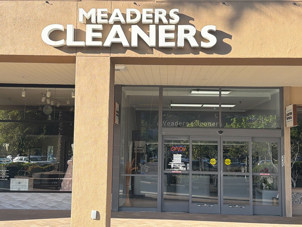 The storefront of Meaders Cleaners with large white signage above glass doors and windows; an "OPEN" sign is visible inside.